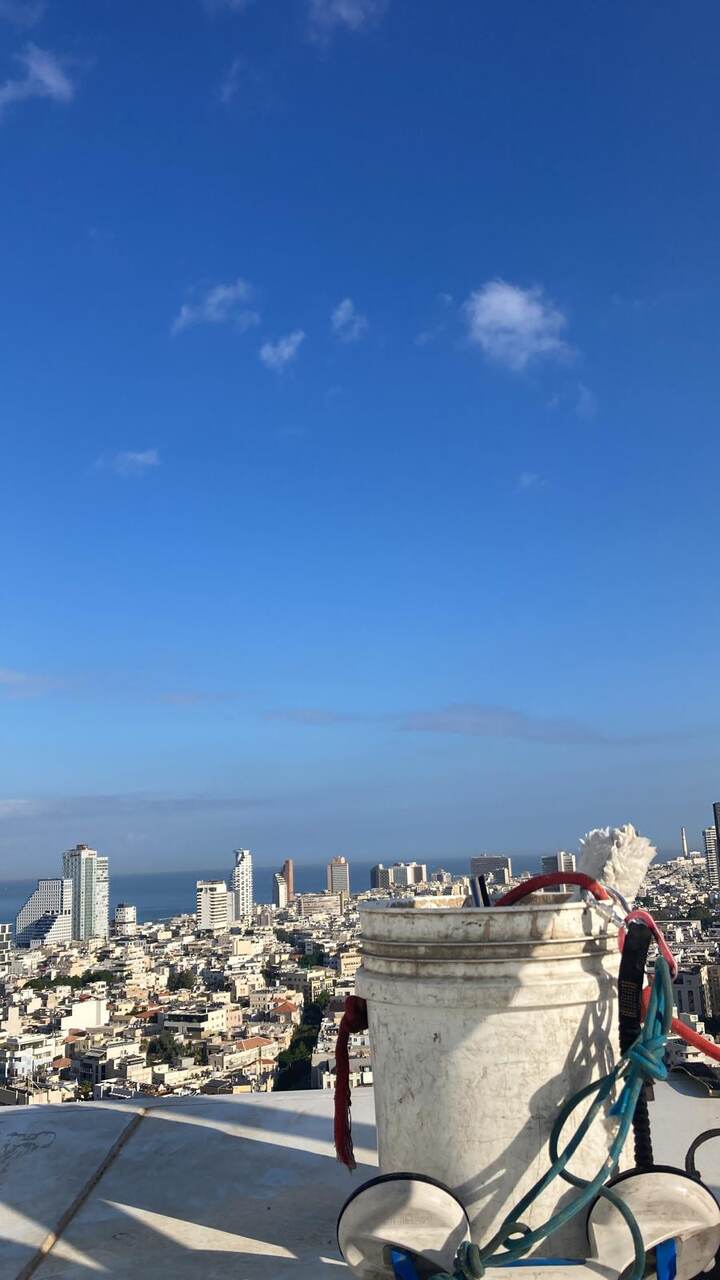 עובד מנקה חלונות וחזיתות זכוכית בגובה בשיטת סנפלינג